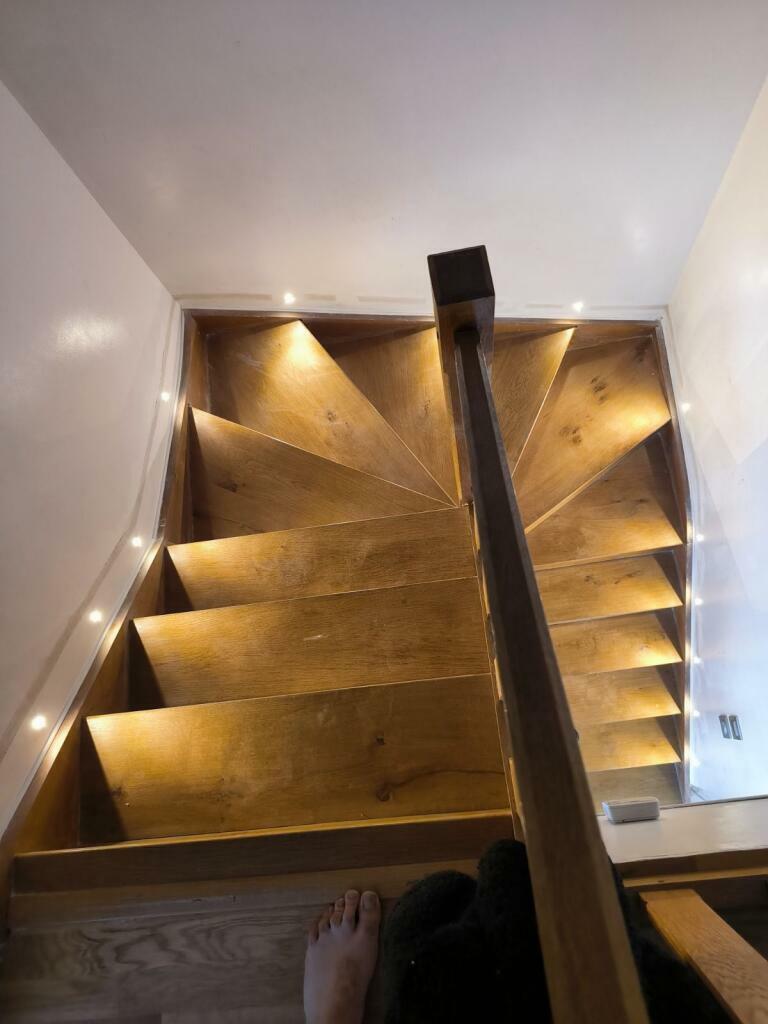 Éclairage LED intégré sous les marches d'un escalier en bois, installation réalisée par GMCM Elec